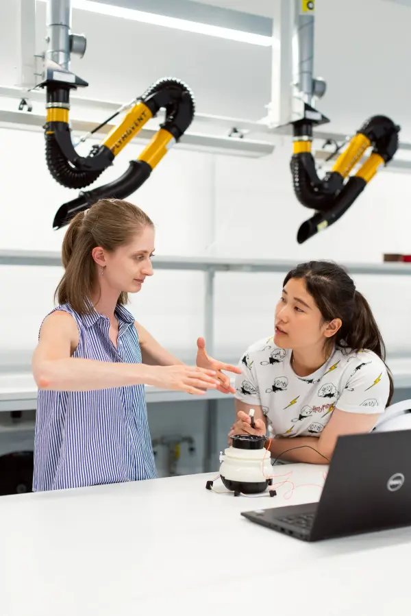 Two women engineers discussing a project in a technical laboratory