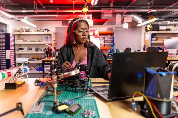 Woman working on electronic equipment beside a laptop