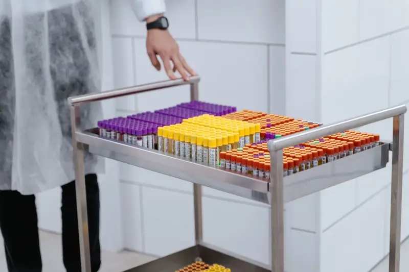 Steel cart holding racks of sample tubes with purple, yellow and orange caps