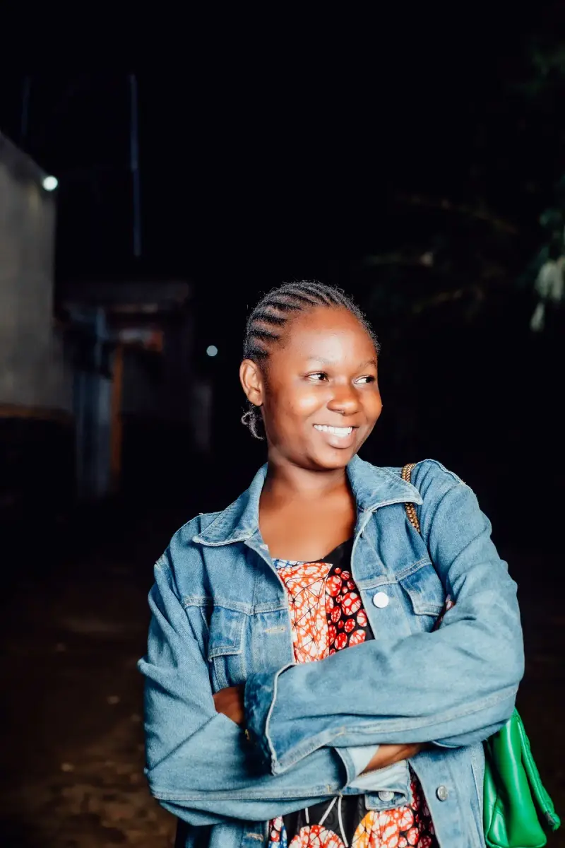 Smiling woman in a denim jacket over a printed dress at night