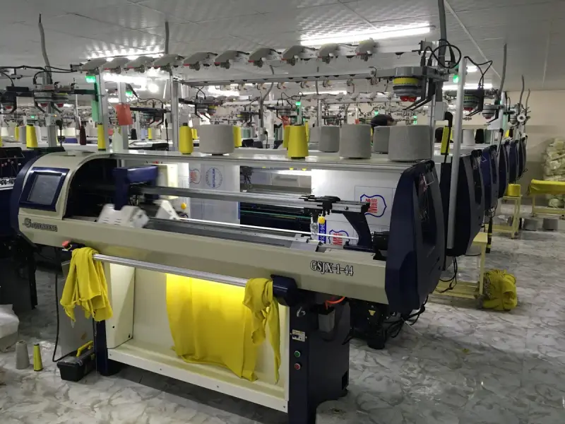 A computerized flat knitting machine running a jacquard pattern