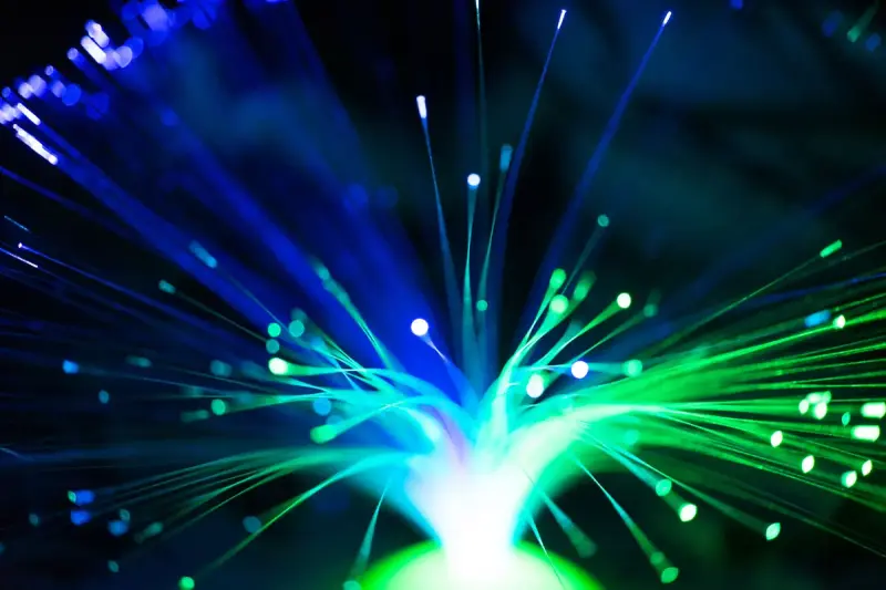 Illuminated fiber optic strands glowing blue and green against a dark background