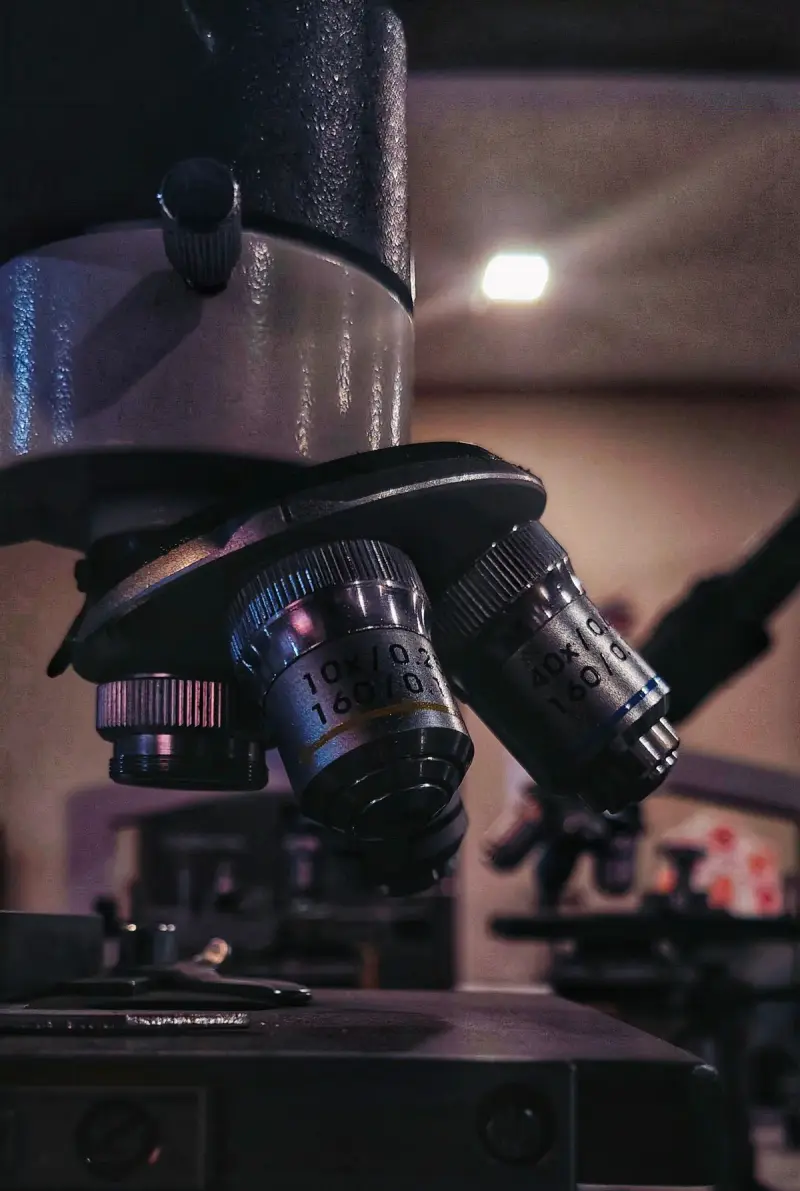 Close view of microscope objective lenses in a dimly lit laboratory