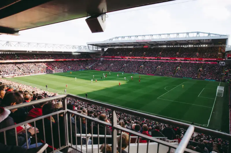 Packed stadium seen from an upper deck as fans watch a match on a green field