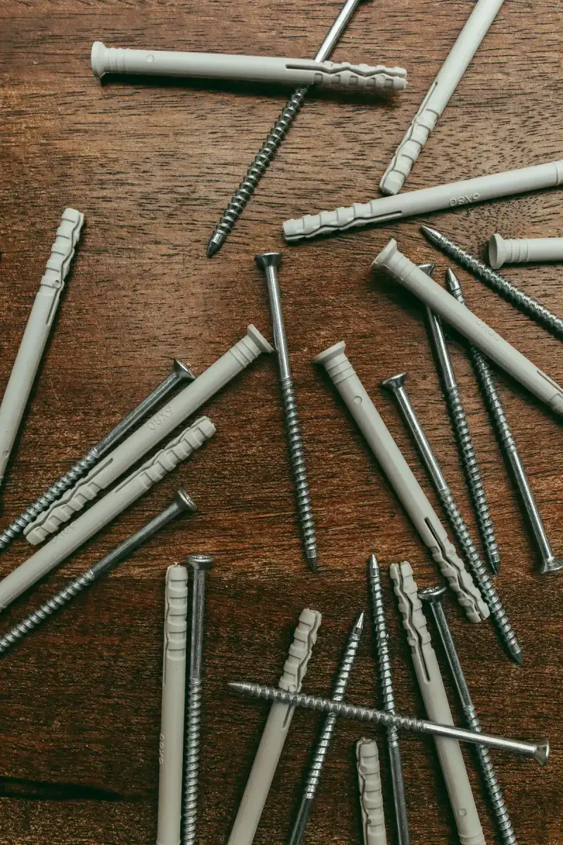 Screws and nylon wall anchors laid out on a wooden surface
