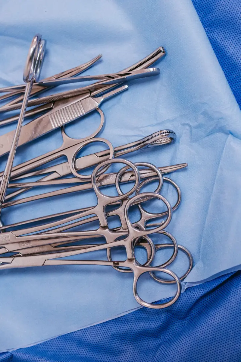 Steel clamps, forceps and scissors laid out on blue sterile drapes