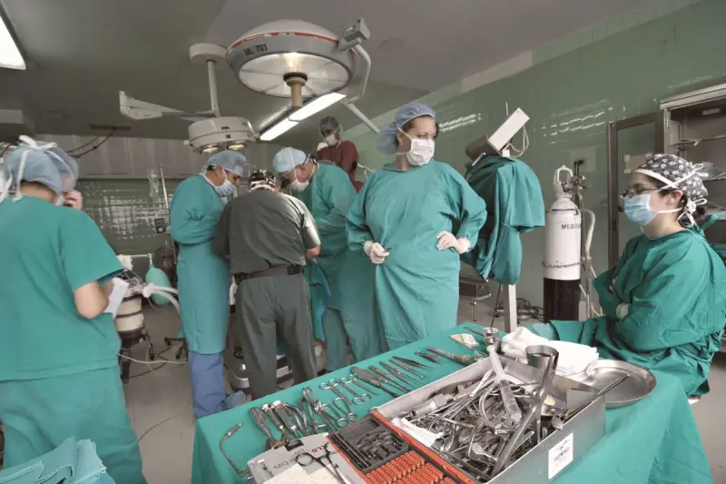 Surgical team of women and men in scrubs around an operating table with imaging cart