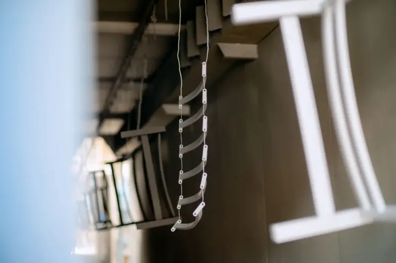 Metal parts hanging from hooks on an overhead conveyor in a coating line