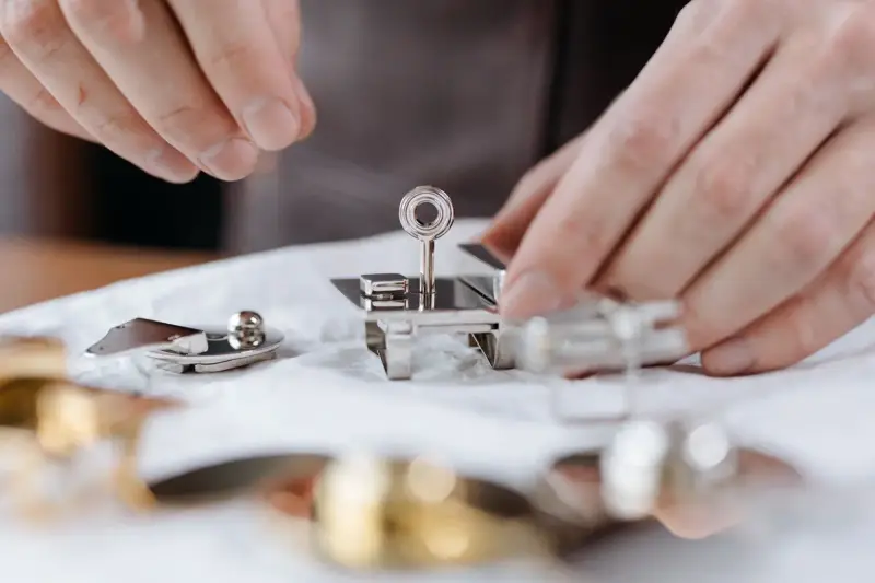 Hands fitting small polished stainless steel parts together on a white cloth