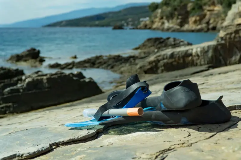 Snorkel, mask and fins resting on a flat rock by a calm sea