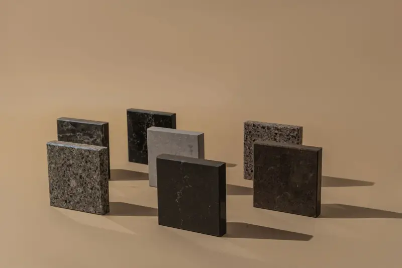 Granite and quartz sample squares standing on a beige surface