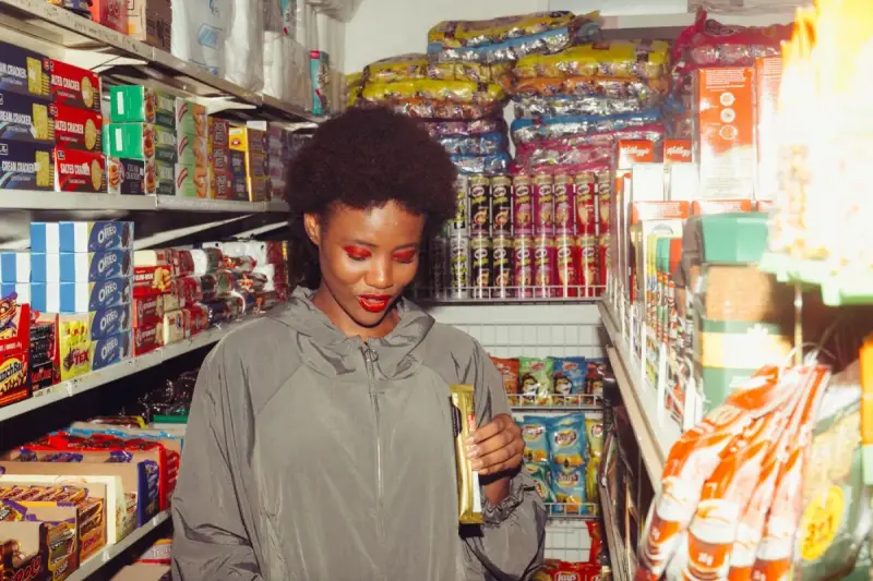 Woman comparing a packaged snack in a colorful grocery-store aisle