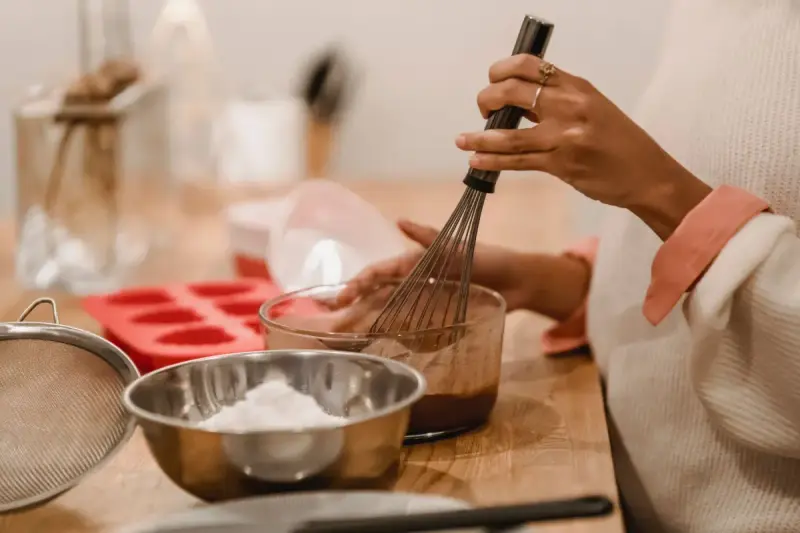 Woman whisking melted chocolate in a glass bowl