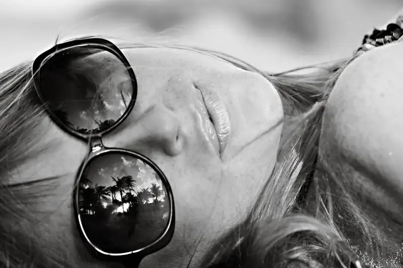Black and white close-up of oversized sunglasses reflecting palm trees on Miami Beach