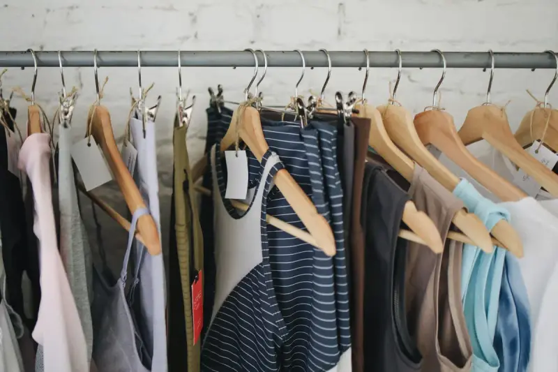 Casual summer clothing on wooden hangers along a boutique rail