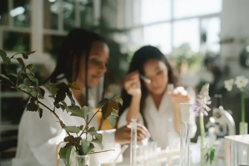 Two scientists working with green plants at a laboratory bench