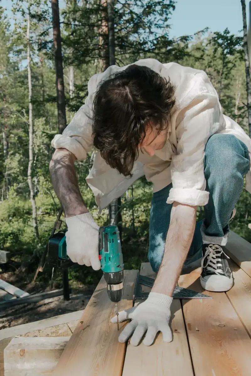 Worker using a drill on wooden decking outdoors