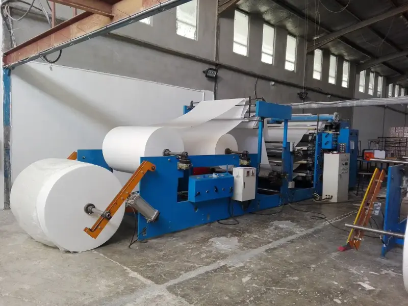 Jumbo paper rolls feed a tissue-converting machine in a factory, photographed in 2017. Paper-