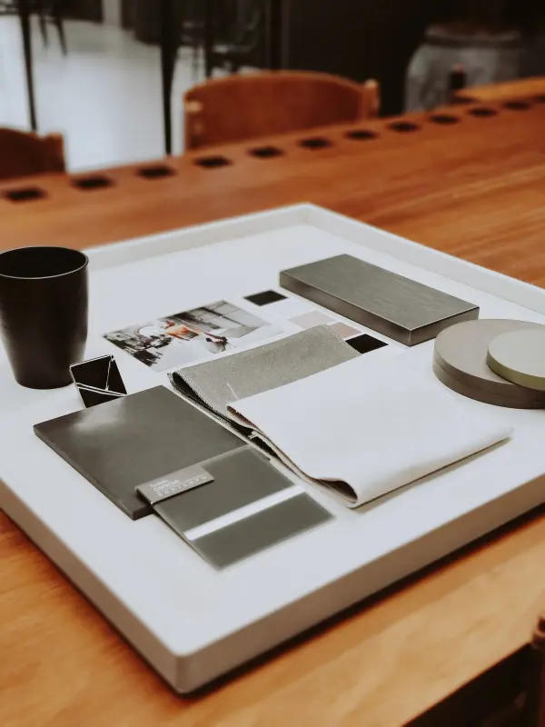 Material and fabric samples arranged on a tray on a wooden desk.