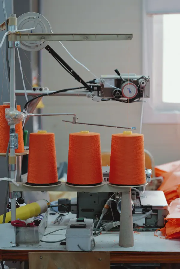 Orange yarn spools and textile machinery in a production setting