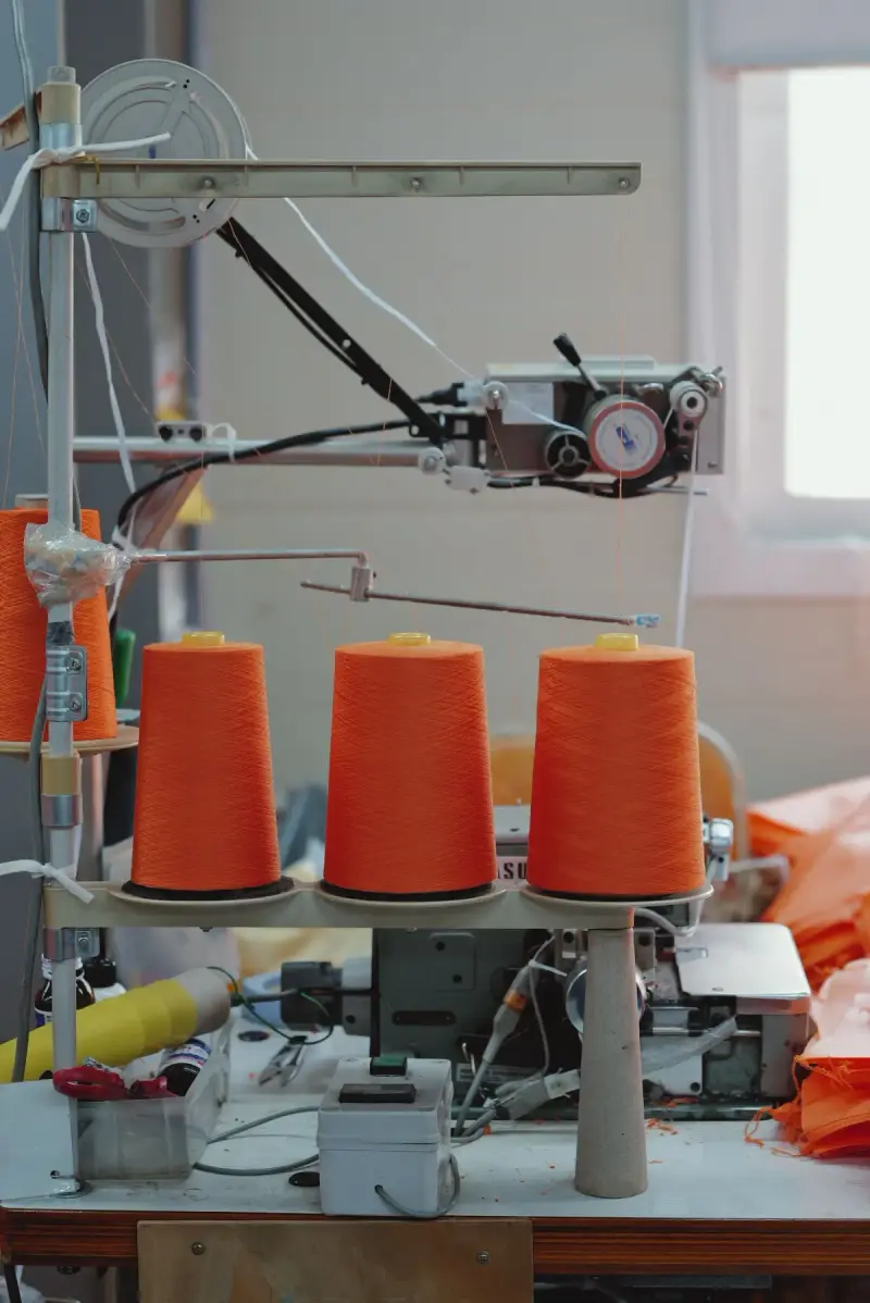 Orange yarn spools and textile machinery in a production setting