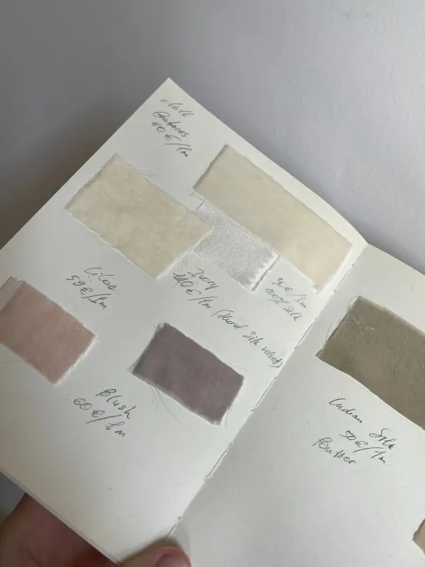 Fabric swatches with handwritten labels arranged in an open sample book.