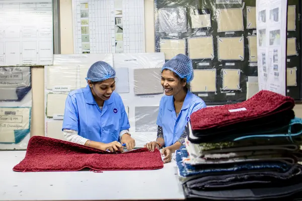 Two female textile workers smiling while reviewing fabric samples at a table