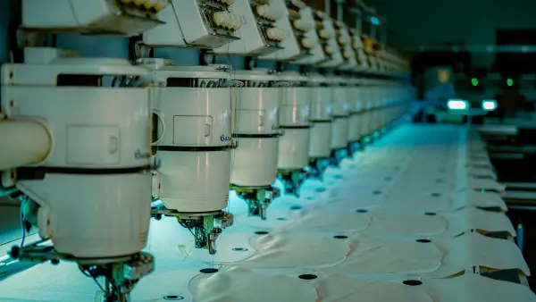 Rows of industrial sewing machines in a textile workshop.