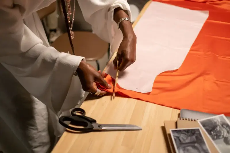 Hands cutting fabric along a pattern on a worktable