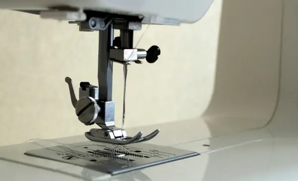 Close view of a sewing machine needle and presser foot.