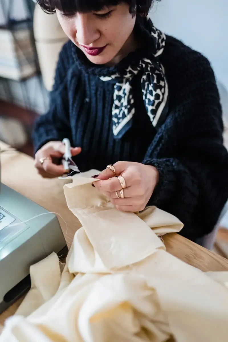 Female garment designer cutting fabric with scissors at a workshop table
