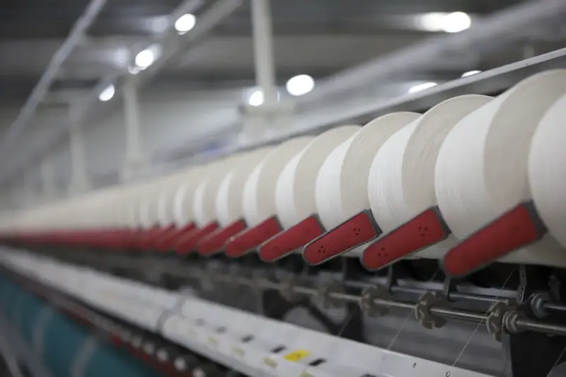 White thread spools running on a textile production line in a factory