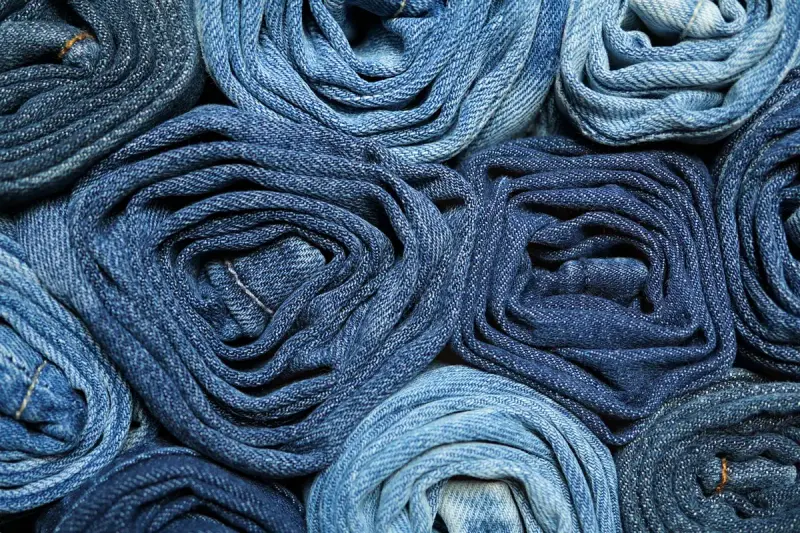 A stack of rolled denim jeans in shades of blue