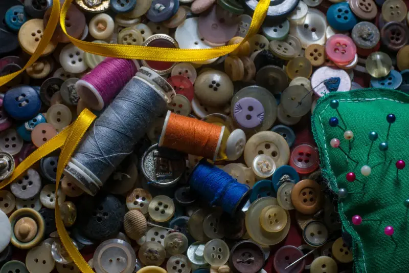 Thread spools, colorful buttons, ribbon and pins arranged on a table