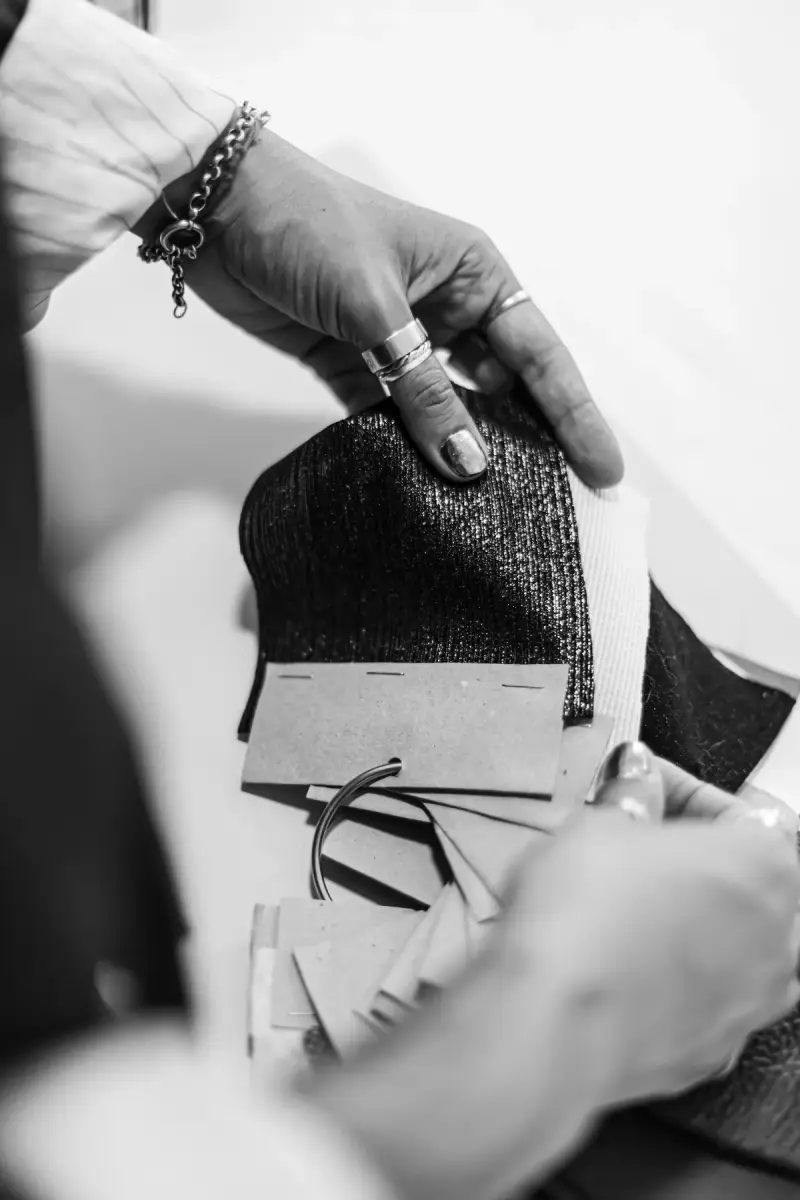 Hands flipping through a book of textured fabric samples in black and white