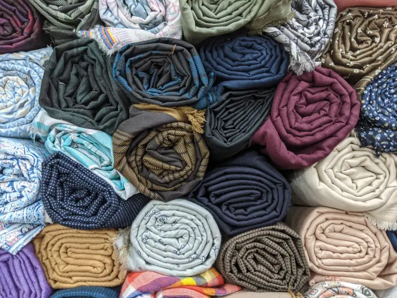 Top view of rolled fabrics in denim blues, greens and earth tones