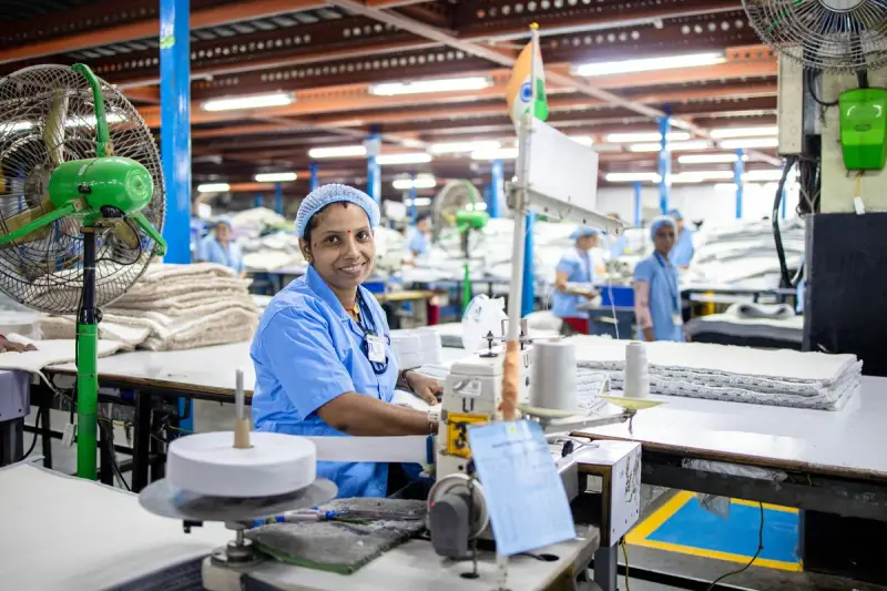 Garment worker at a sewing machine in a bright textile factory