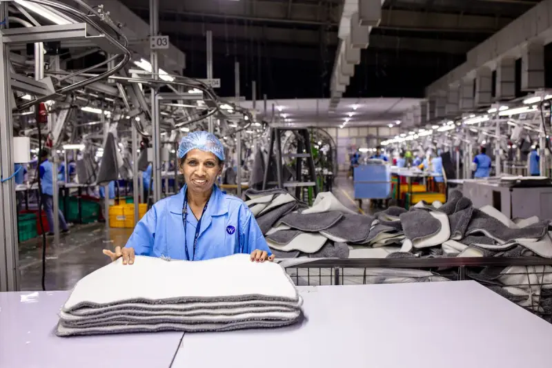 Textile worker folding finished fabric at a table in a factory