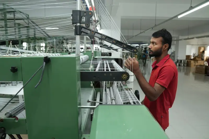 Man operating a weaving machine in a textile mill