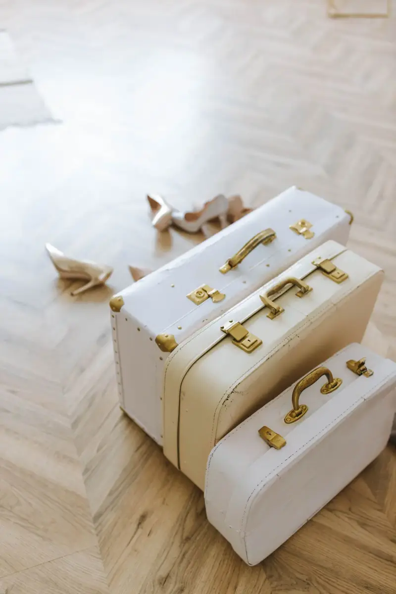 Stack of three cream vintage-style suitcases with gold hardware on a parquet floor