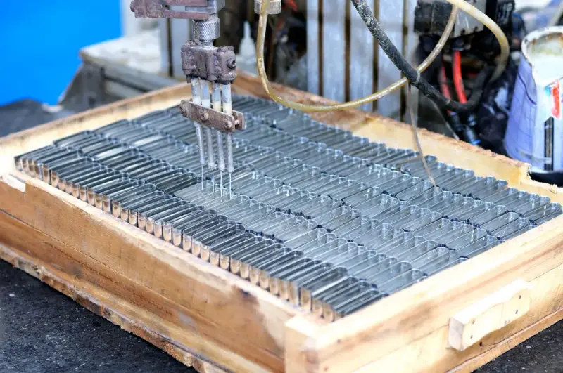 Automated machine head placing rows of small metal parts into a wooden tray