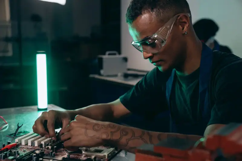 Technician in safety glasses assembling components on a circuit board