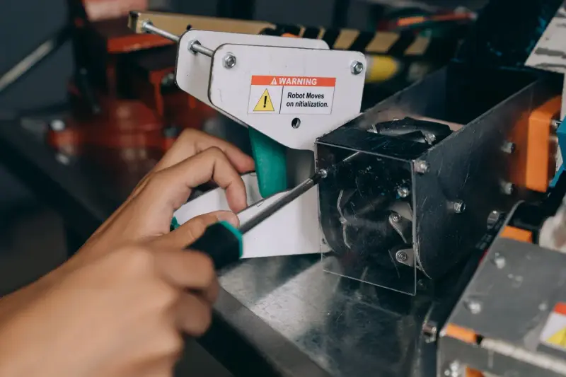 Hand driving a screw into a sheet-metal bracket on an automated assembly fixture