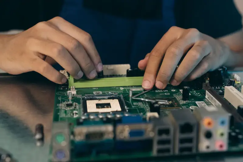 Technician pressing a memory module into a motherboard slot on a workbench