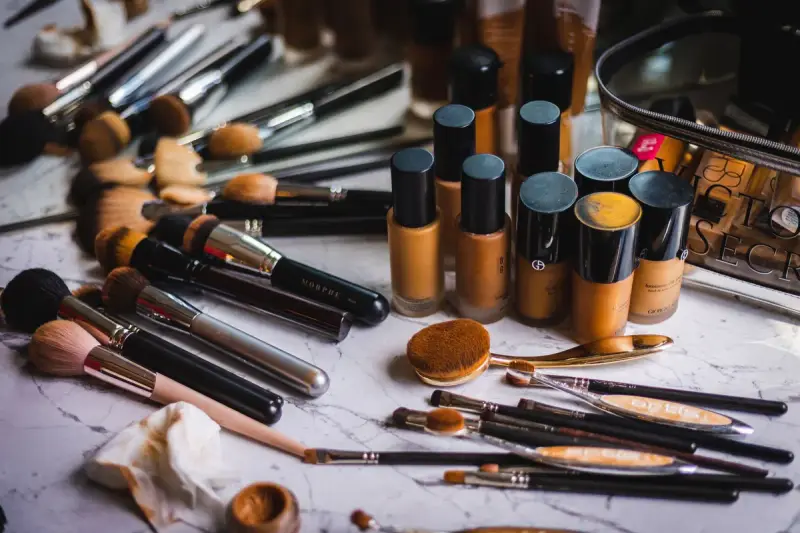 Foundation bottles, sponges and brushes spread across a marble counter