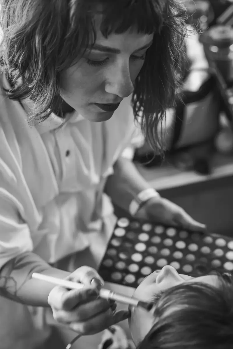 Makeup artist with a palette working on a model backstage in black and white