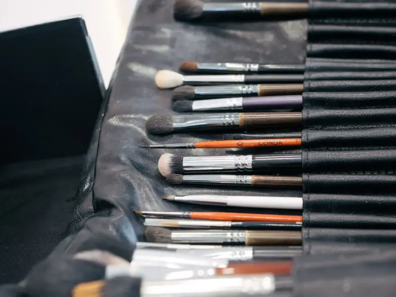 Row of professional makeup brushes lined up in a black brush roll
