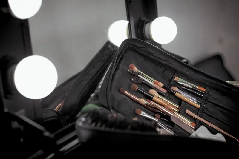 Brushes in a black pouch on a vanity lit by round bulbs