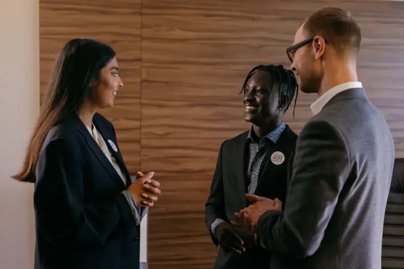 Three professionals with name badges talking at a meeting