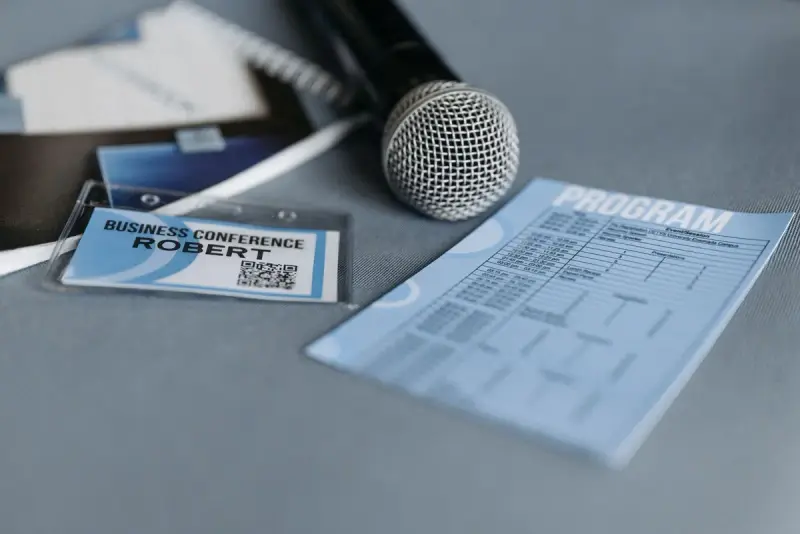 Conference badge, program and microphone on a table